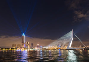 Zalmhaventoren verlicht tijdens lichtshow voor de opening in Rotterdam. De blauwe lichtbundels schieten als een waaier de lucht in.